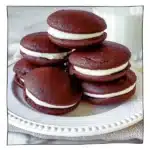 Stack of fluffy, egg-free chocolate whoopie pies with marshmallow filling on a white plate