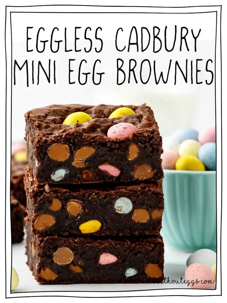 Three rich and fudgy eggless brownies loaded with Cadbury Mini Eggs stacked on a white surface with colorful candies scattered around.